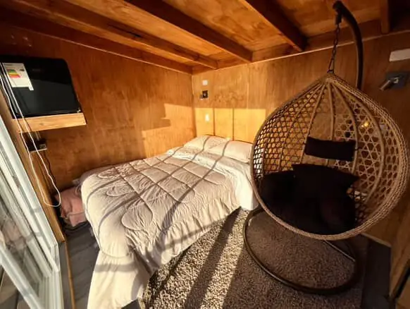 Dormitorio con cama doble y silla colgante